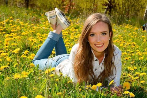 Young woman lying in a meadow of dandelion