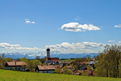 Village with the Parish Church of the Assumption in front of Alps
