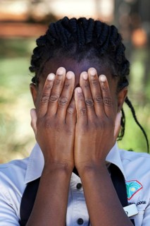 Namibian woman of the Ovambo tribe holding hands in front of her face