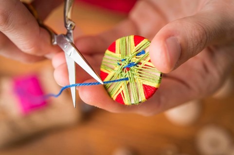 Button maker cutting blue yarn