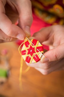Button maker stitching and wrapping red and yellow yarn into star pattern