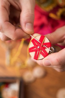 Button maker stitching and wrapping red and yellow yarn into star pattern