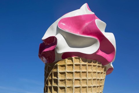 Large ice sculpture made of plastic as advertisement for an ice cream parlour in front of a blue sky
