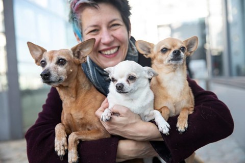 Laughing woman holding her three dogs in her arms