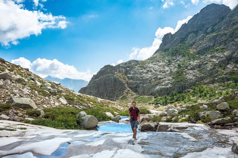 Young man hiking by the river Golo in the mountains
