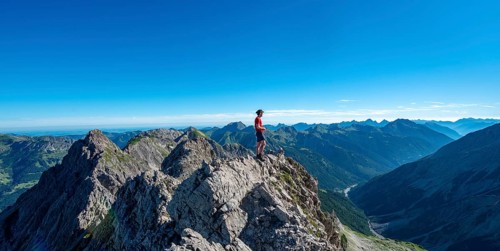 Hiker stands on rocks looking into the distance