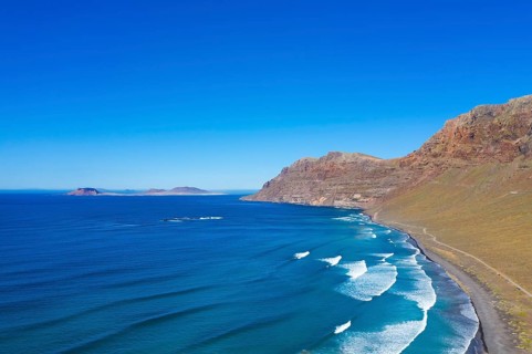 View on beach Playa Famara with mountain range Risco de Famara