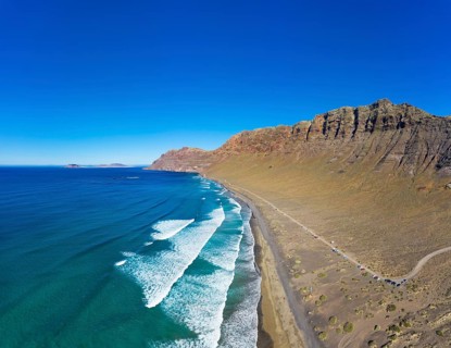 View on beach Playa Famara with mountain range Risco de Famara