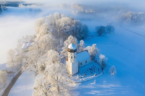Snow-covered church St. Johann Baptist. Fog mood