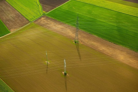 High-voltage transmission lines over farm fields in spring