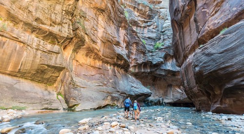 Hikers walking through river