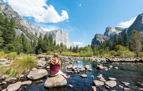 Young woman sitting on stone in River Merced