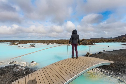 Tourist on a wooden bridge at the Blue Lagoon near Gratdavik