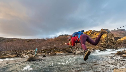 Young woman crossing river with rope