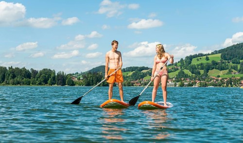 Young man and woman standing on paddle boards