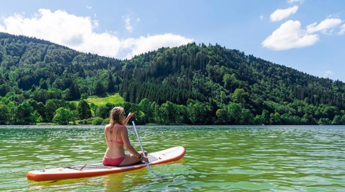 Young woman sitting on a Standup-Paddle Board or SUP