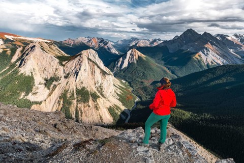 Female hiker looks from summit over mountain landscape