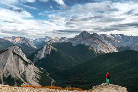 Female hiker views from summit over mountain landscape
