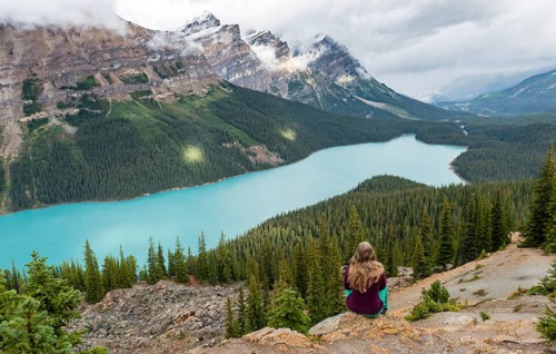 Young woman sitting on a stone looking into nature
