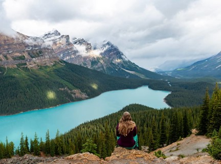 Young woman sitting on a stone looking into nature