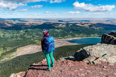 Young hiker standing at the view of mountain lake Lower Two Medicine Lake with mountain landscape