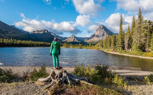 Young woman looking at mountain lake Two Medicine Lake in mountain landscape
