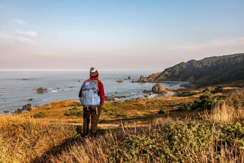 Young woman on a hiking trail along the rugged coast with many rocks
