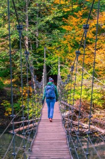 Young woman walking on a suspension bridge across a river