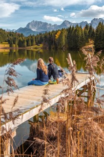 Two young women sitting at a jetty having a snack