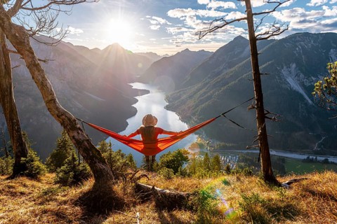 Woman with a sun hat sitting in an orange hammock