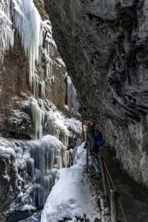 Young woman in the icy Partnachklamm with icicles and snow in winter