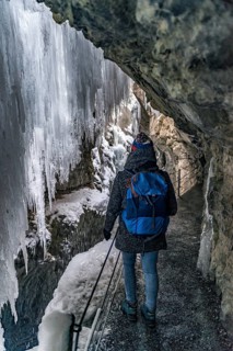 Young woman in the icy Partnachklamm with icicles and snow in winter