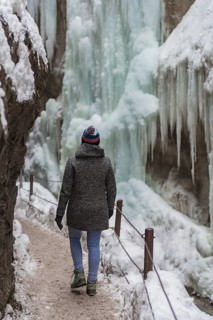Young woman in the icy Partnachklamm with icicles and snow in winter