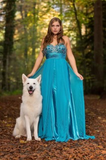 Woman with long turquoise-blue evening dress and white shepherd dog