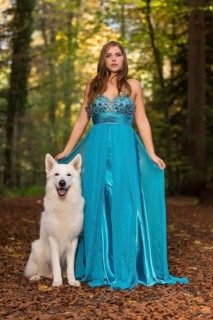 Woman with long turquoise-blue evening dress and white shepherd dog