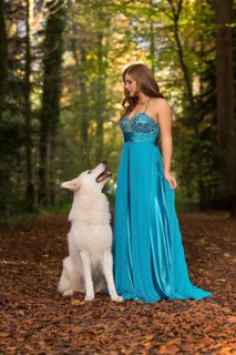 Woman with long turquoise-blue evening dress and white shepherd dog