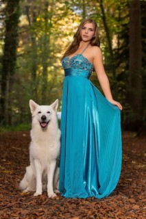 Woman with long turquoise-blue evening dress and white shepherd dog
