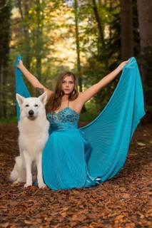Woman with long turquoise-blue evening dress and white shepherd dog