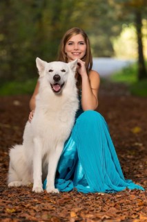 Woman with long turquoise-blue evening dress and white shepherd dog