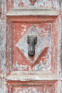 Old door with door knocker in shape of a hand