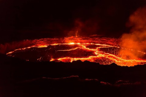 Glowing lava lake with eruptions at night
