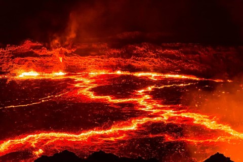 Glowing lava lake with eruptions at night