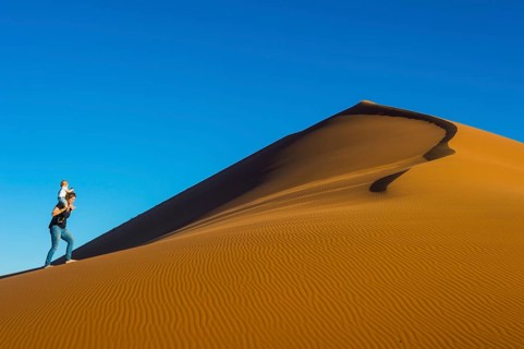 Woman with her baby walking up the giant sanddune Dune 45