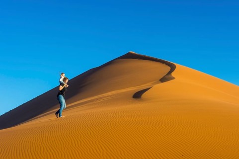 Woman with her baby walking up the giant sanddune Dune 45