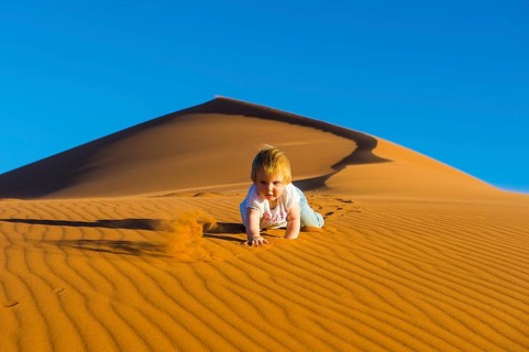 Baby crawling down in the sand