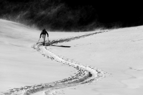 Ski mountaineer in winter landscape against a dark background