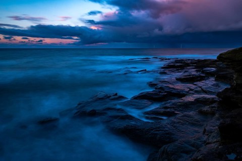 Rocky coast with dramatic dark clouds at sunset