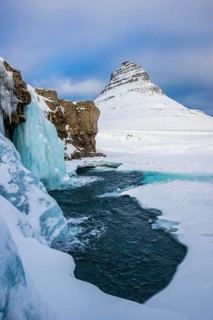 Frozen waterfall Kirkjufellsfoss and the mountain Kirkjufell with snow