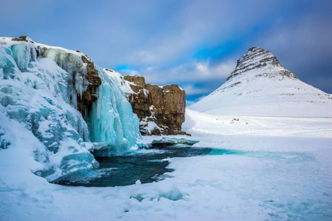 Frozen waterfall Kirkjufellsfoss and the mountain Kirkjufell with snow