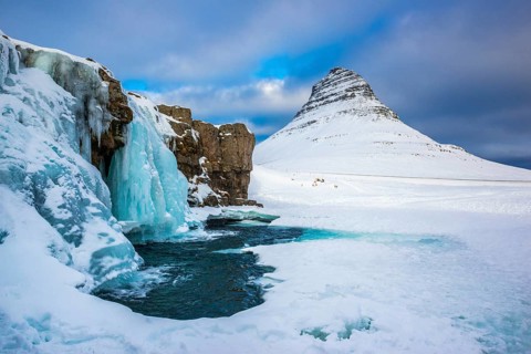 Frozen waterfall Kirkjufellsfoss and the mountain Kirkjufell with snow